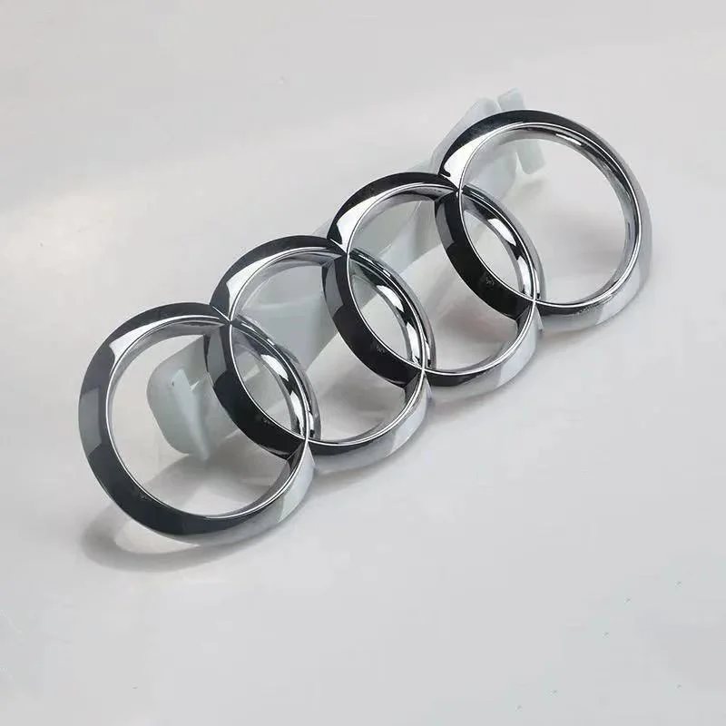 Emblème chromé à quatre anneaux entrelacés sur un support blanc en plastique