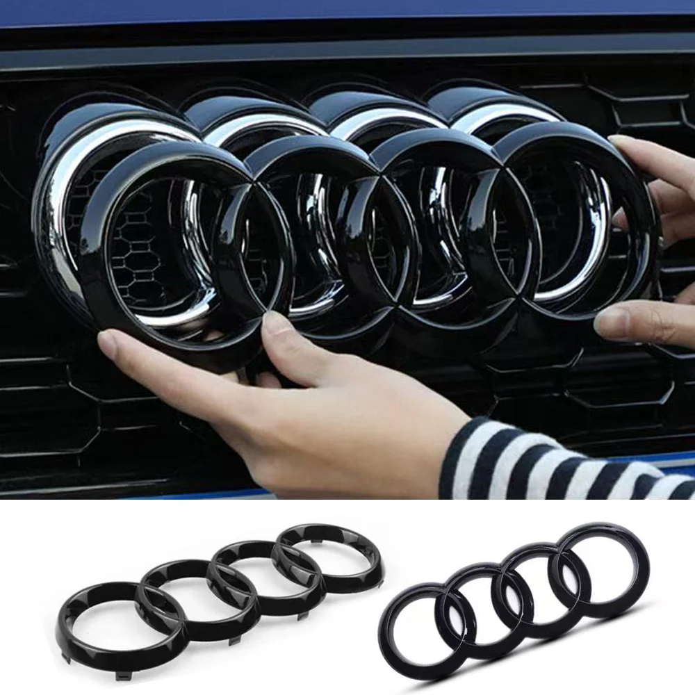 Mains installant un emblème noir brillant à quatre anneaux sur la calandre avant Audi