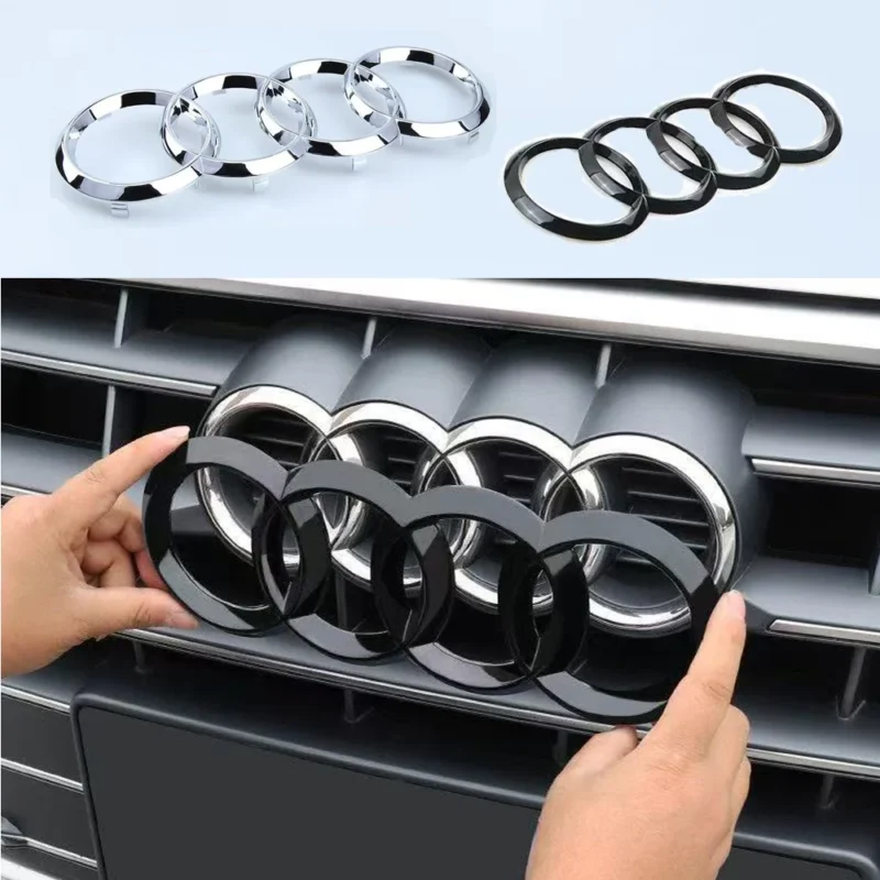 Mains installant un emblème Audi noir sur la calandre avant d'un véhicule automobile