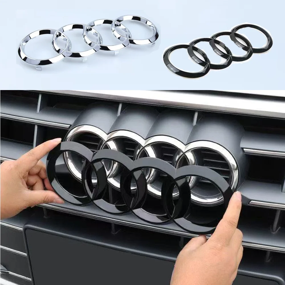 Mains installant un emblème Audi noir sur la calandre avant d'un véhicule automobile