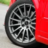 S13095741fbc448609e14405cfbd338e2T.webp Centre de roue Audi noir et argent installé sur une jante grise