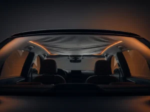Habitacle de voiture dans la pénombre, ciel de toit en tissu qui s’affaisse sous un liseré lumineux orange