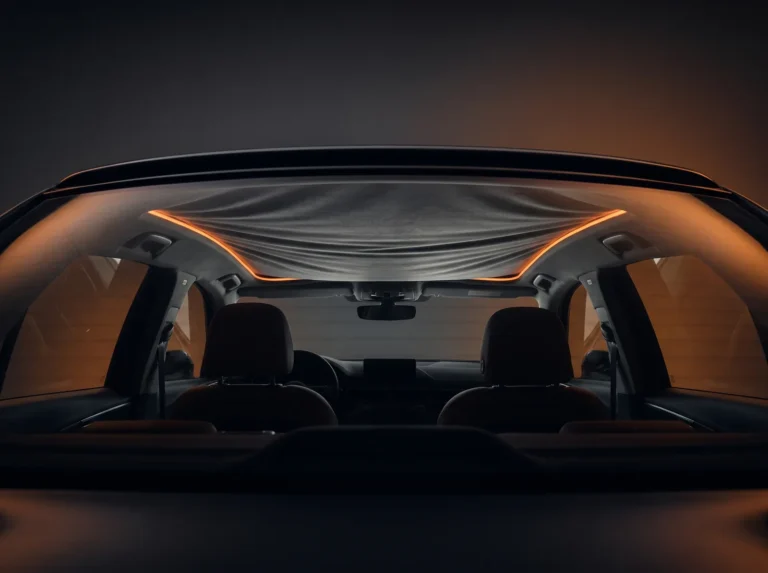 Habitacle de voiture dans la pénombre, ciel de toit en tissu qui s’affaisse sous un liseré lumineux orange